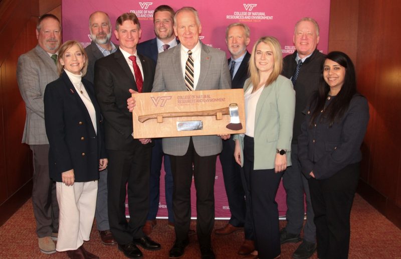 Dean Paul Winistorfer (center) holds a commemorative ax presented to him try the College of Natural Resources and Environment in honor of his service to the college.