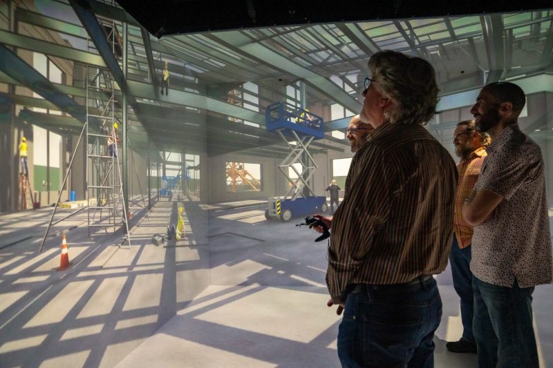 a small group views a virtual construction site in a 3D visualization cube