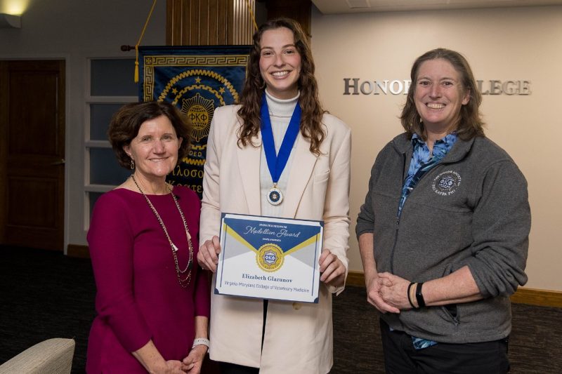 Three people smiling for the camera. One person has a certificate and medal.