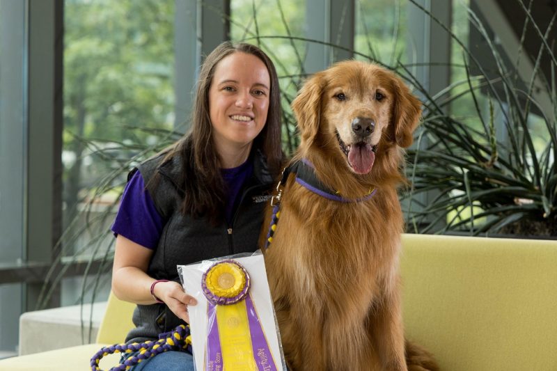 Person and dog sitting on a couch with a ribbon.