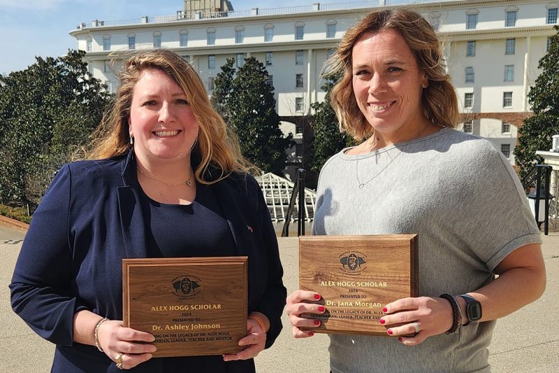 Two people holding wooden plaques.