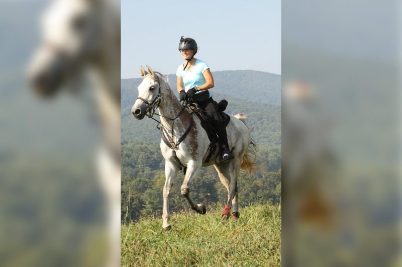 Claire Godwin riding a horse in the mountains.